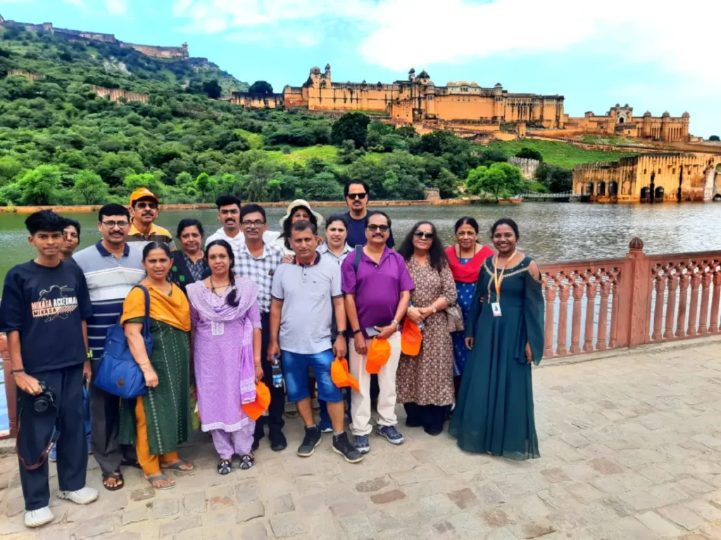 Tour group posing near Amber Fort Jaipur with palace and lake in background